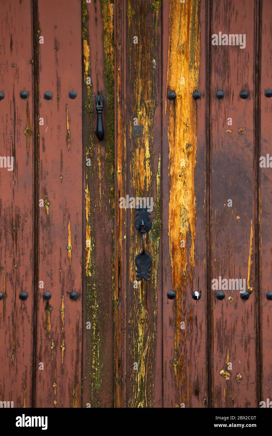 Old rustic wooden door with different layers of cracked paint in orange and yellow colors Stock Photo