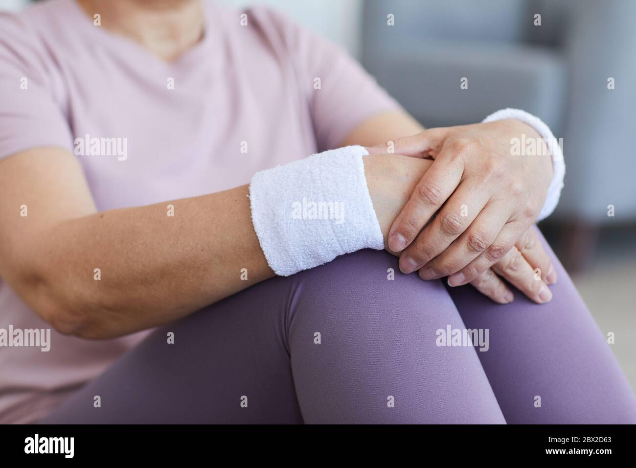 Close-up of senior woman with sports bracelets on her hands sitting and resting after sports training Stock Photo