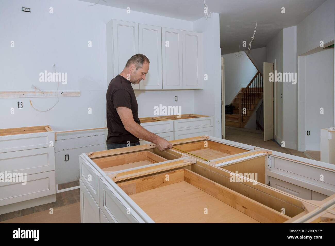 Man interior designer using tape measure on on domestic kitchen counter home improvement Stock Photo