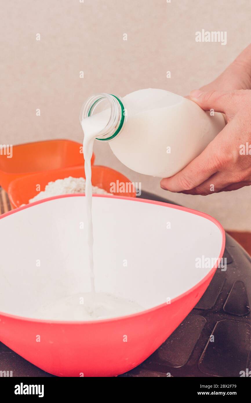 Mixing batter for pancakes vertical frame adding milk, eggs, flour