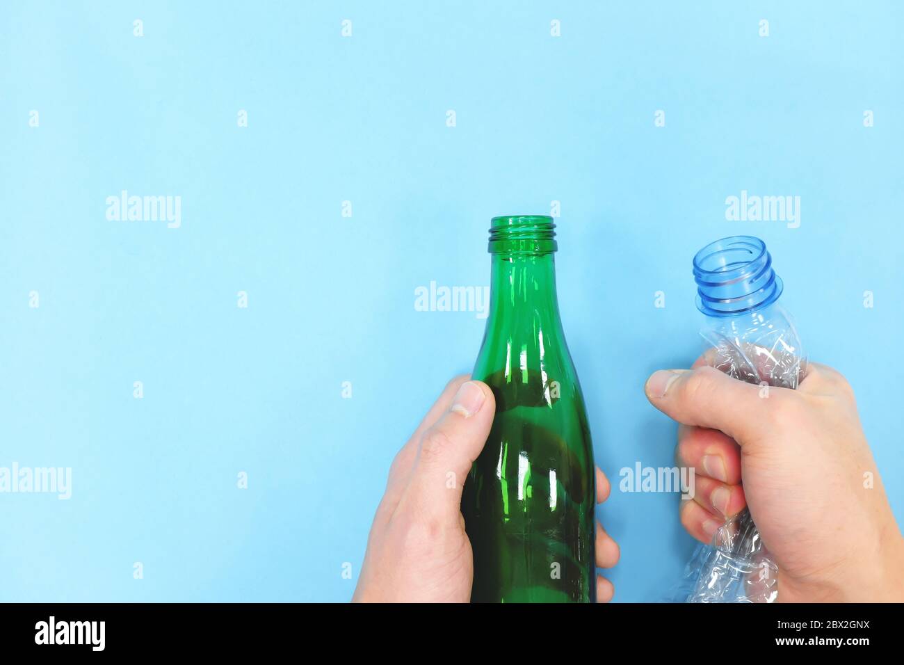 Hands holding empty plastic and glass bottle in blue background. Go