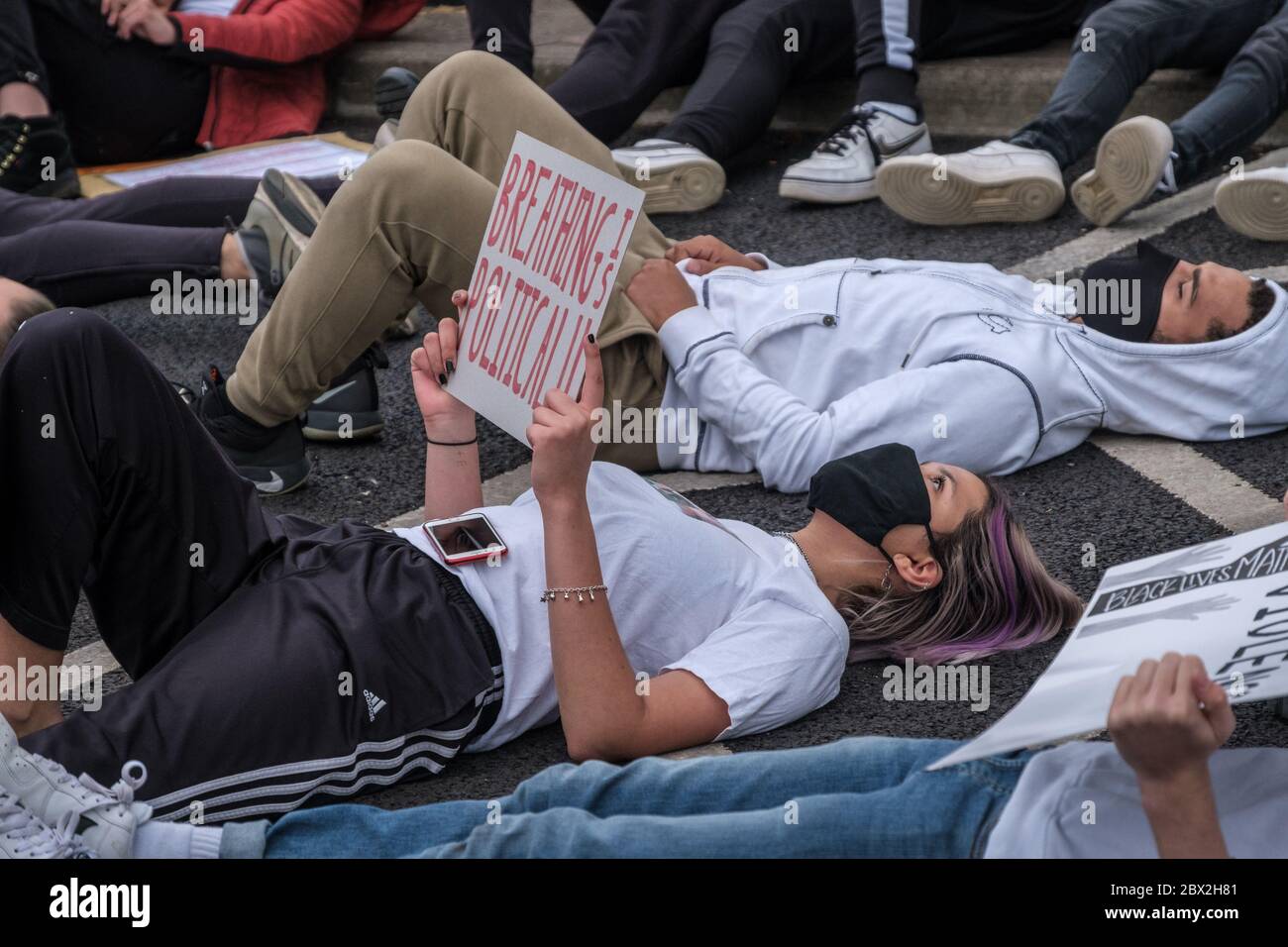 Staines, Surrey, UK. 4th June 2020. Several hundred young local residents take part in a silent die-in for 8 minutes 46 seconds in the Two Rivers shopping park in the centre of Staines, the time Floyd was restrained by a police officer. They had marched around Staines with placards shouting 'Black Lives Matter' and 'I can't Breathe' in protest against the death of George Floyd and others who have died at the hands of police in the USA and here in the UK and had 'taken the knee' at the side of the old Town Hall before marching to the shopping park.  Peter Marshall/Alamy Live News Stock Photo