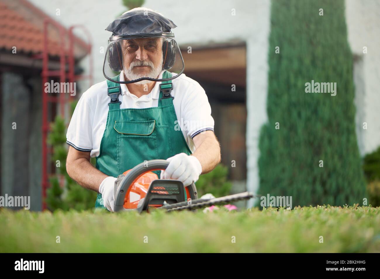 Eldery man landscaping in garden and looking at camera. Front view 