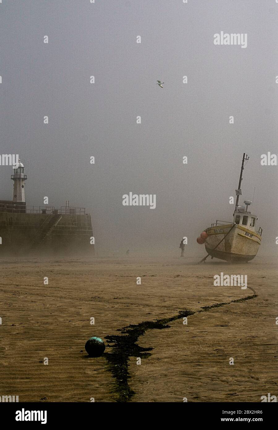 Fishing boat grounded at low tide in harbour. Stock Photo