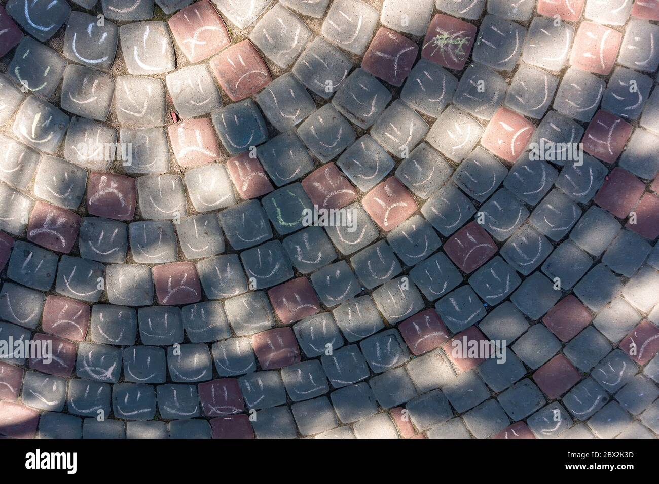 Сhalk drawing on asphalt. Face cartoon smiley and sad. Top view of paving stones with kids art. Stock Photo