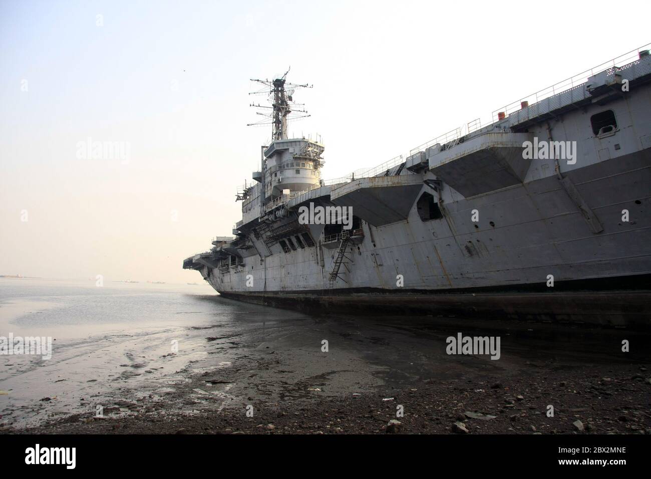 Shipbreaking Yard in Darukhana, Mumbai, India – INS Vikrant dismantling with scrap metal & workers in background Stock Photo
