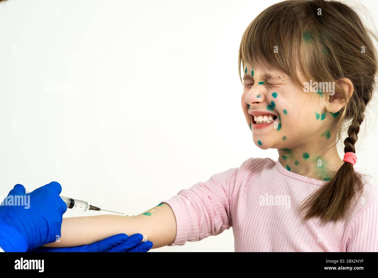 Doctor making vaccination injection to an afraid child girl sick with chickenpox, measles or rubella virus. Vaccination of children at school concept. Stock Photo