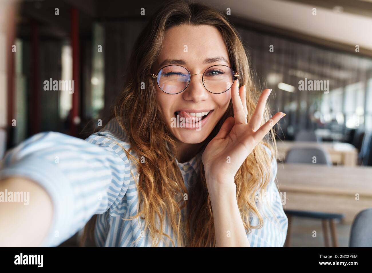 Image of happy beautiful woman winking and taking selfie photo while ...