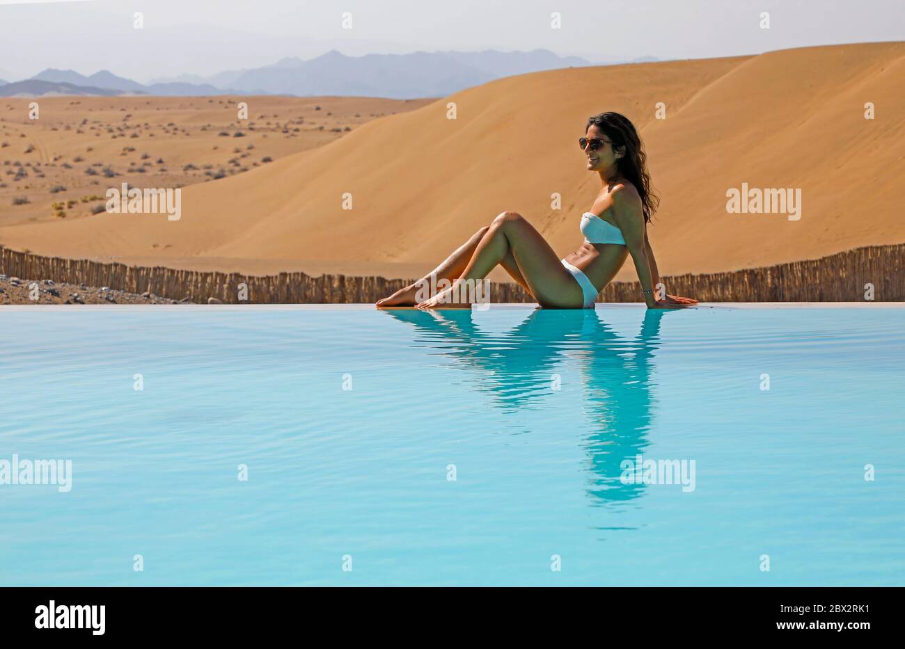 Oman sultanate, arabic peninsula, Dunes luxury tented hotel and resort located on sand dunes one hour from Mascate and airport, local beauty in swimming dress by the swimming pool Stock Photo