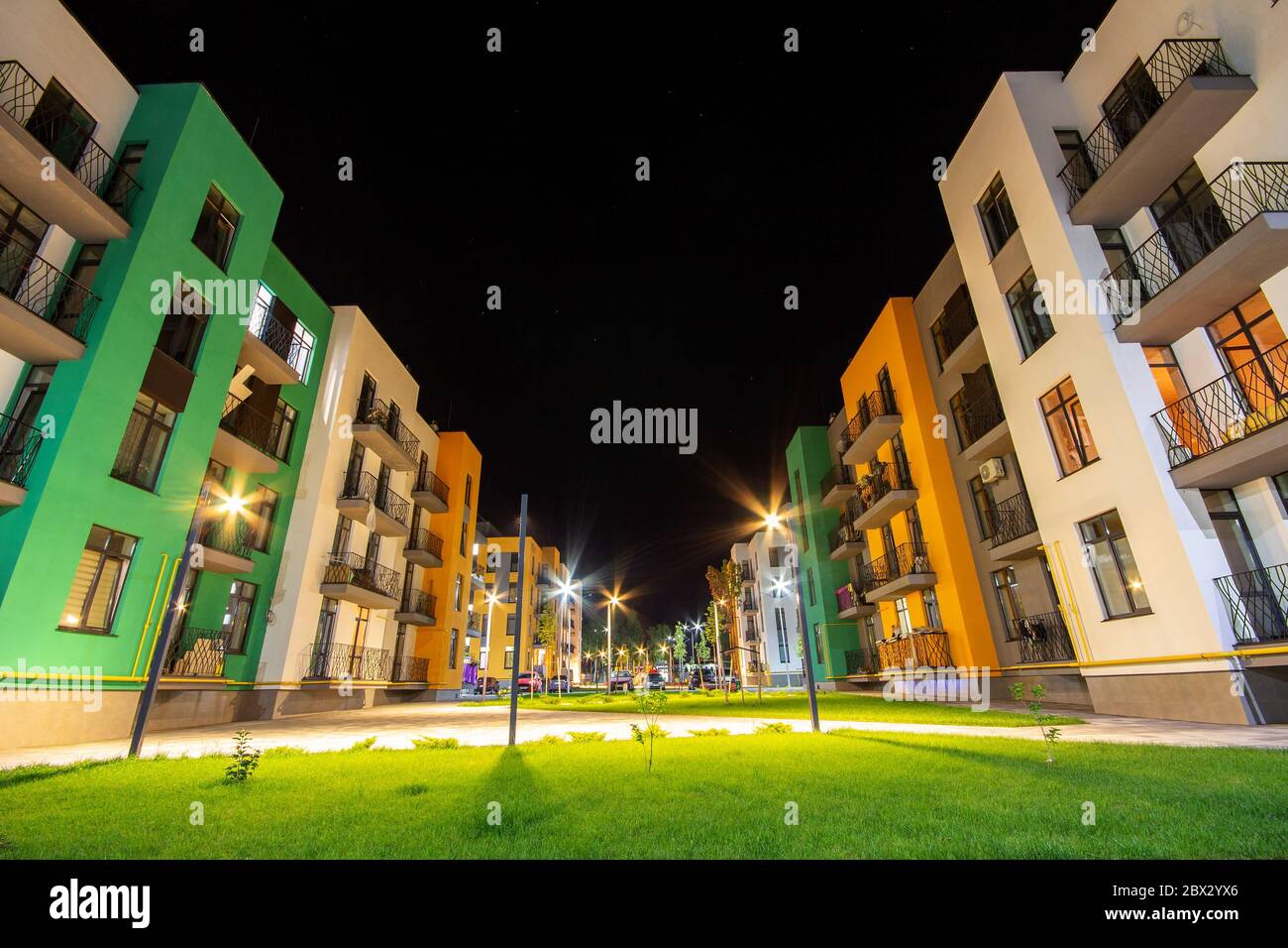 Yard between residential apartment buildings with green grass lawns and