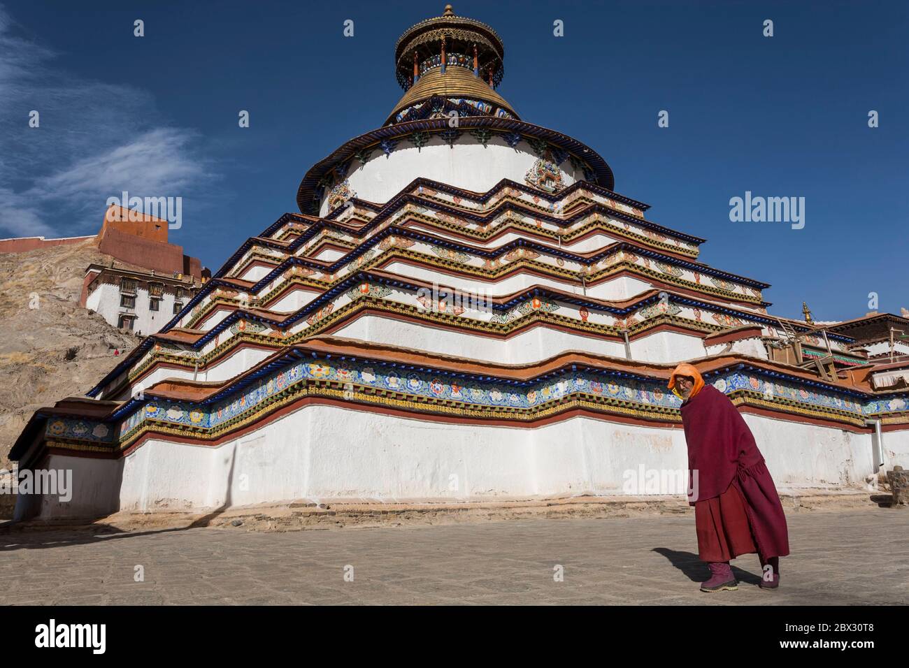 China, Tibet Autonomous Region, Gyantse, Pelkor Chode monastery, monk passing in front of the Kumbum, large chorten with multiple ornate chapels, altitude 4000 m Stock Photo
