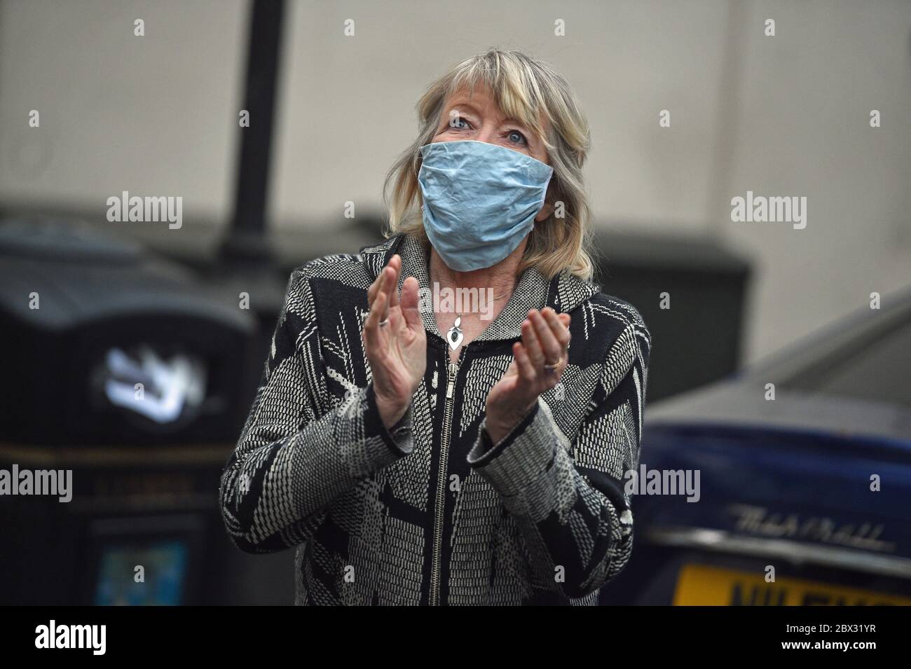 A woman outside the Chelsea and Westminster Hospital, London, joins in applause during a Clap for Carers to recognise and support NHS workers and carers fighting the coronavirus pandemic. Stock Photo