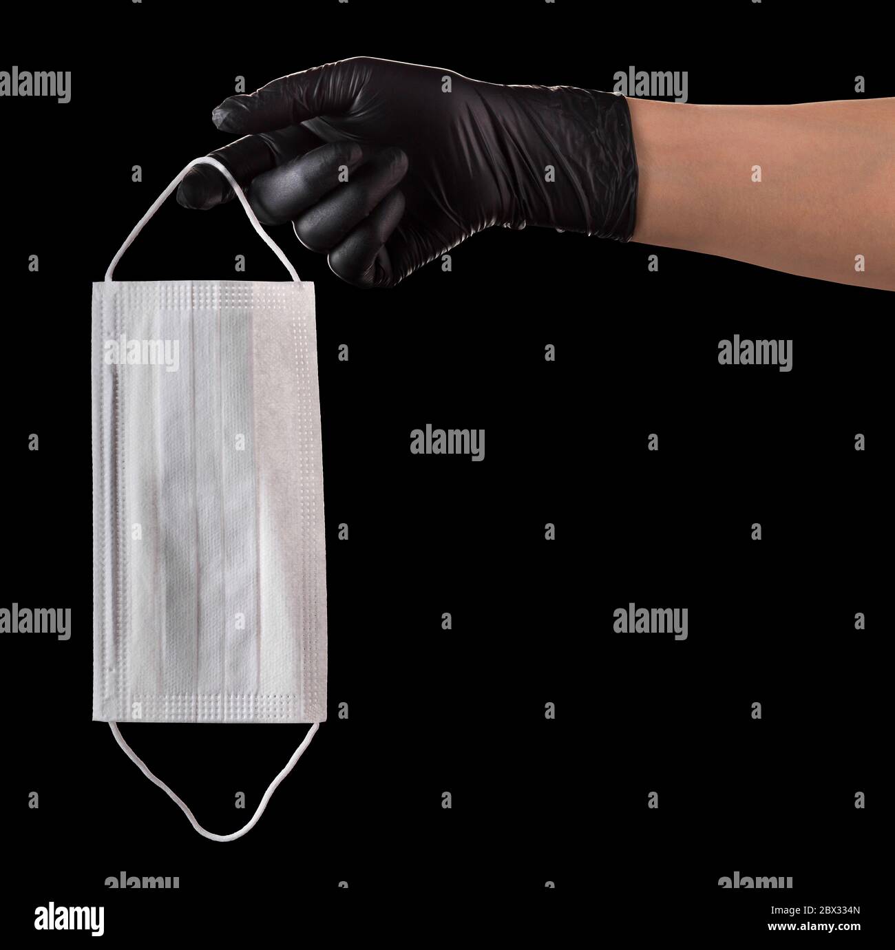 Hand in black gloves holding disposable face mask isolated on black ...