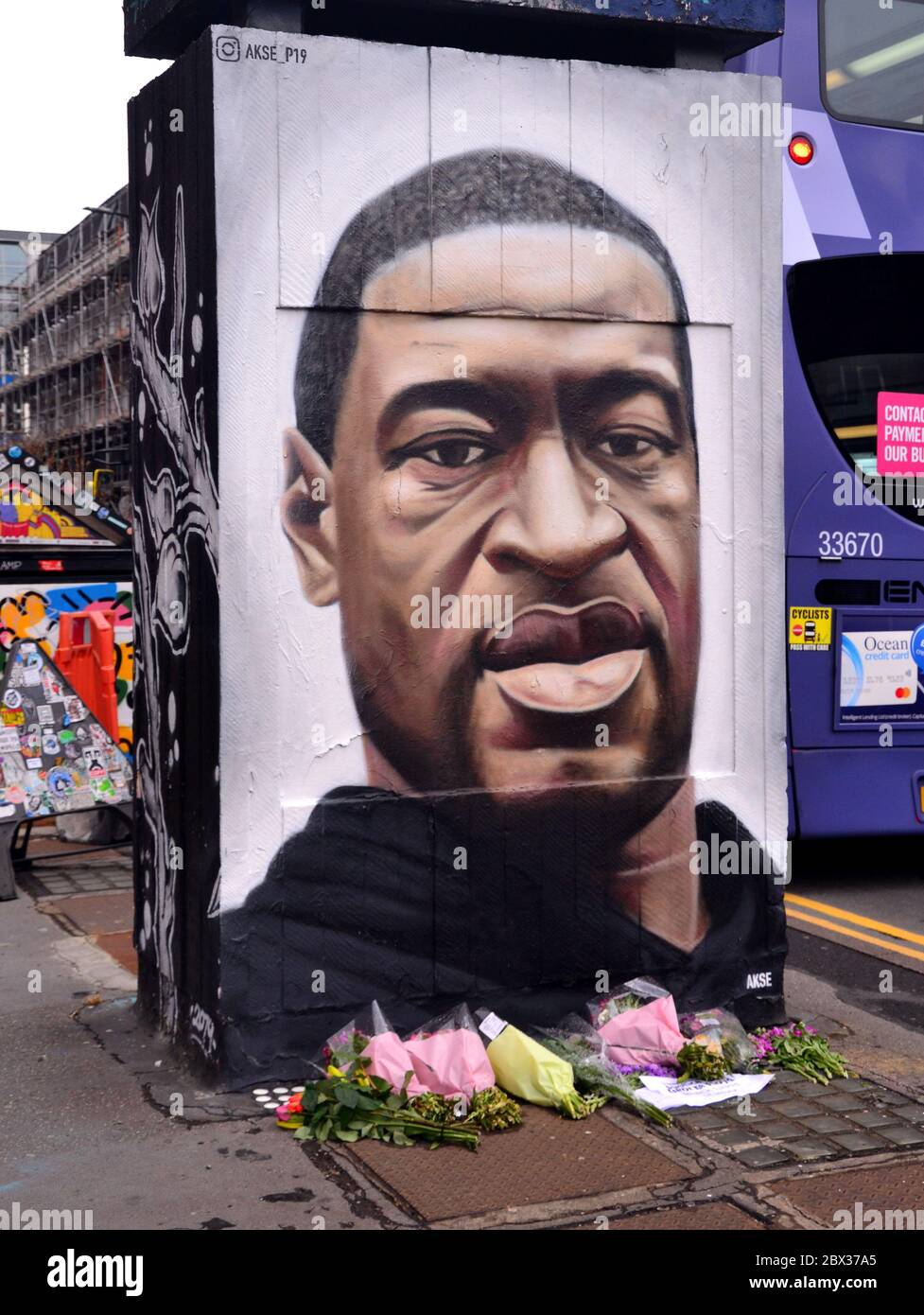 Flowers have been left at a mural depicting George Floyd, painted by street artist Akse, which has recently appeared in Stevenson Square, central Manchester, England, United Kingdom. Floyd, an African-American man, died in Minneapolis, Minnesota, United States, on May 25, 2020, while being arrested by 4 police officers after a shop assistant alleged he tried to pay with a counterfeit $20 bill. Stock Photo