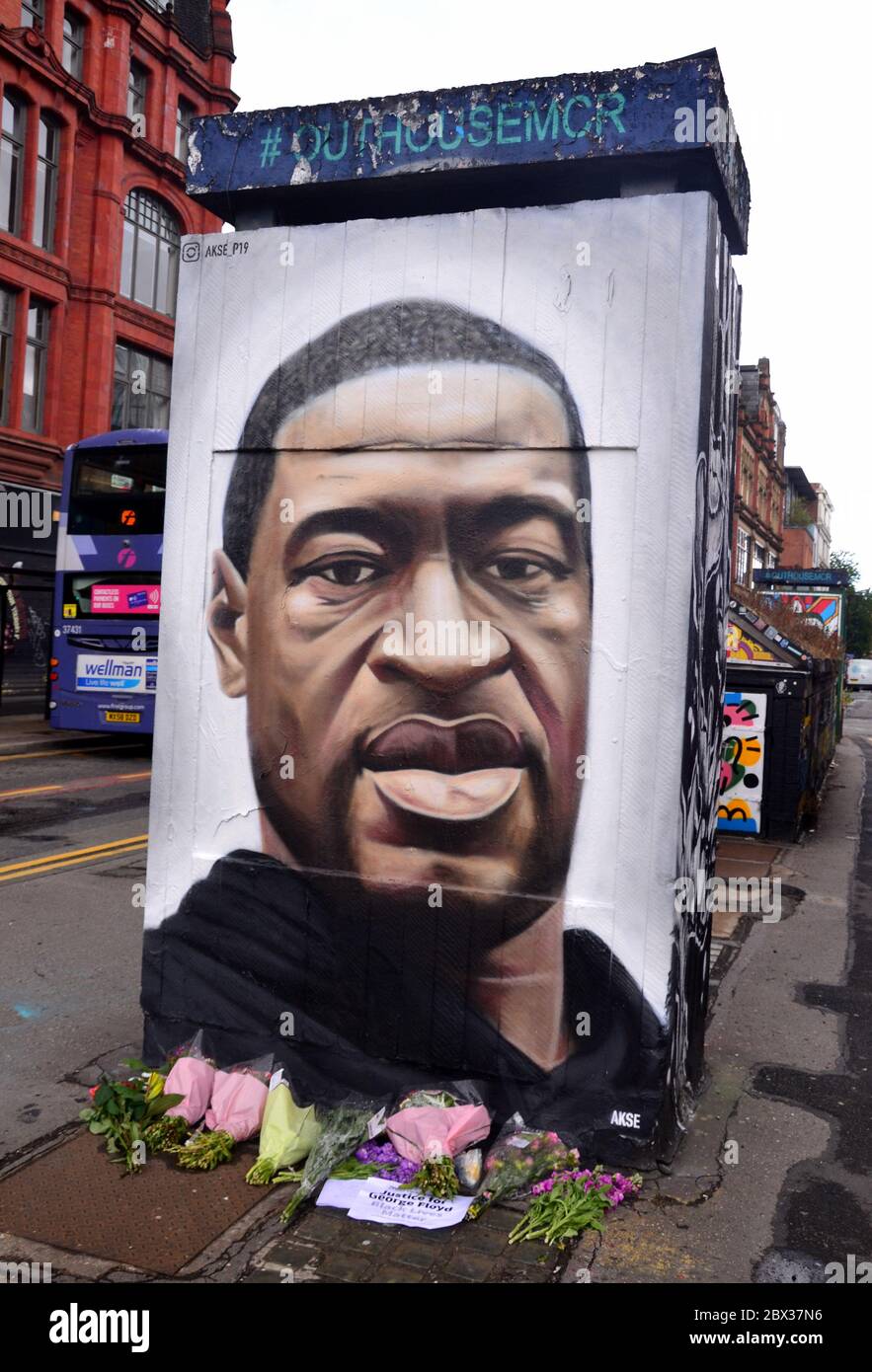 Flowers have been left at a mural depicting George Floyd, painted by street artist Akse, which has recently appeared in Stevenson Square, central Manchester, England, United Kingdom. Floyd, an African-American man, died in Minneapolis, Minnesota, United States, on May 25, 2020, while being arrested by 4 police officers after a shop assistant alleged he tried to pay with a counterfeit $20 bill. Stock Photo