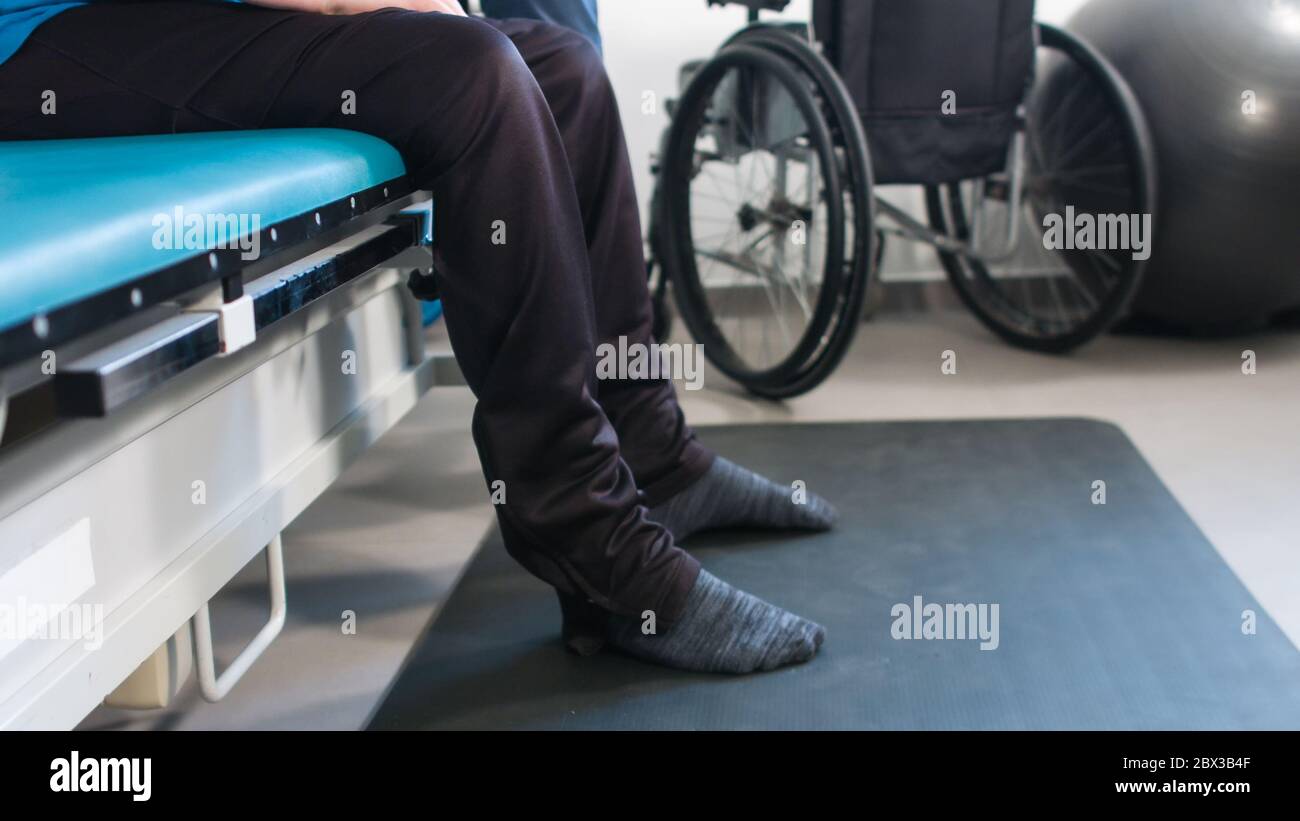 Physiotherapist exercising with disabled person using wheelchair on a therapy table Stock Photo