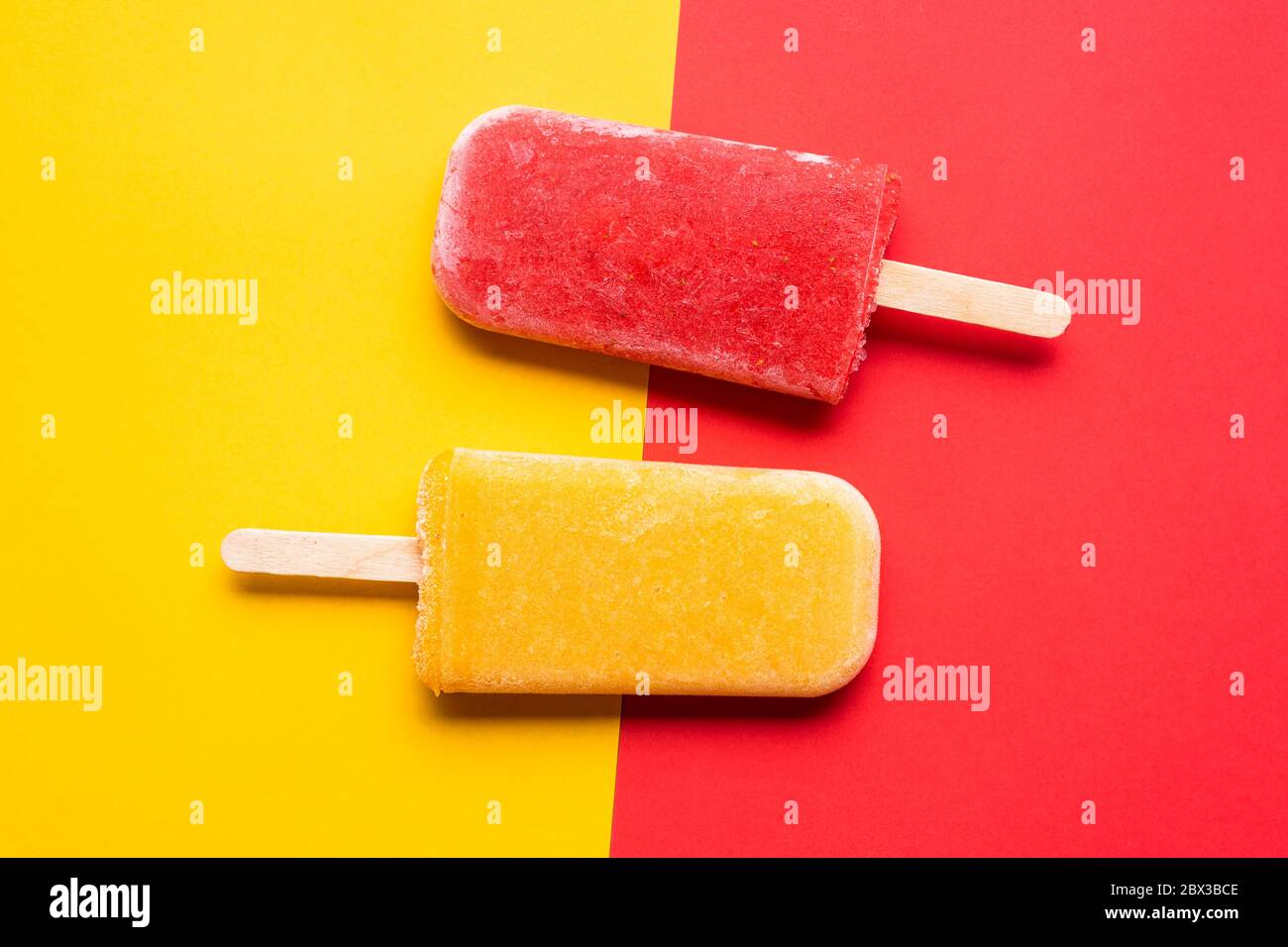 Two popsicles ice cream on a yellow and red background, above view