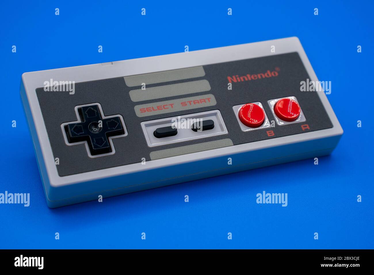 Nintendo NES controller. Close-up of vintage classic gamepad with a colorful blue background. Malaga, Spain - June 04, 2020 Stock Photo