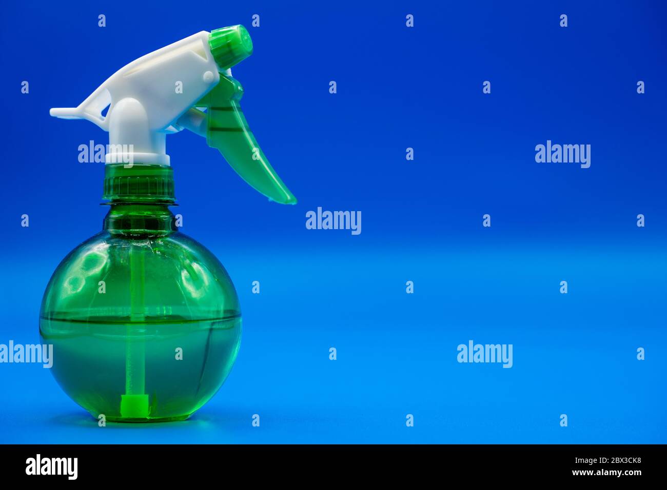Plastic spray bottle with copy space. Liquid sprayer isolated in a colorful blue background. Stock Photo