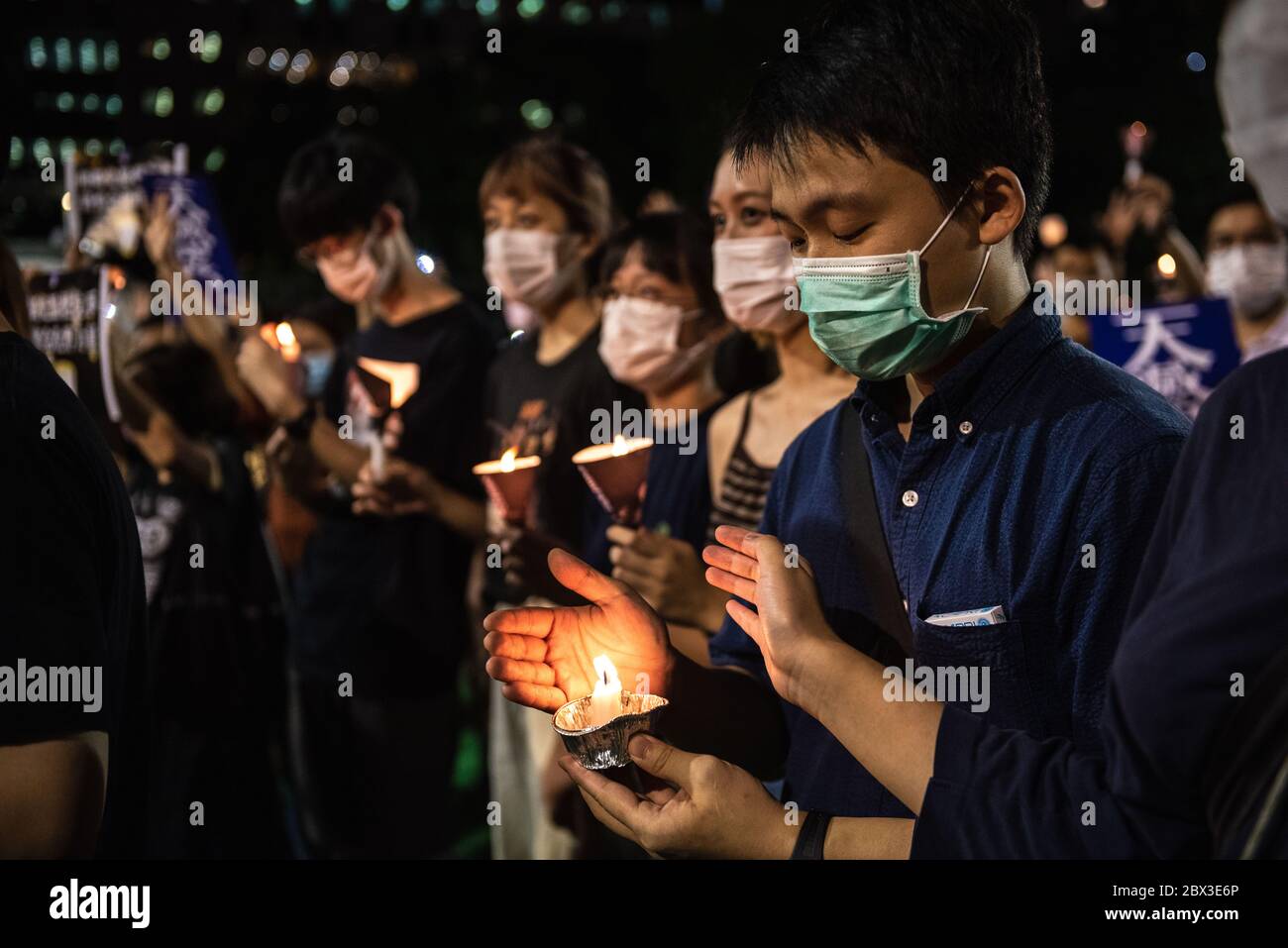 Participants shield their candles from the wind during the anniversary rally.Thousands of Hong Kong residents attended a rally commemorating the 31st anniversary of the Tiananmen Square Massacre. Rally attendees chanted slogans, lit candles and held a moment of silence in remembrance of the day. Stock Photo