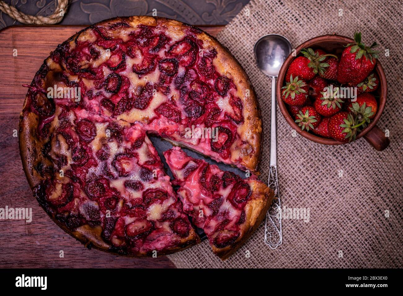 Traditional homemade strawberry cake dessert with fresh strawberry on vintage wooden background. Dark food photo, rustic style, natural light. Stock Photo