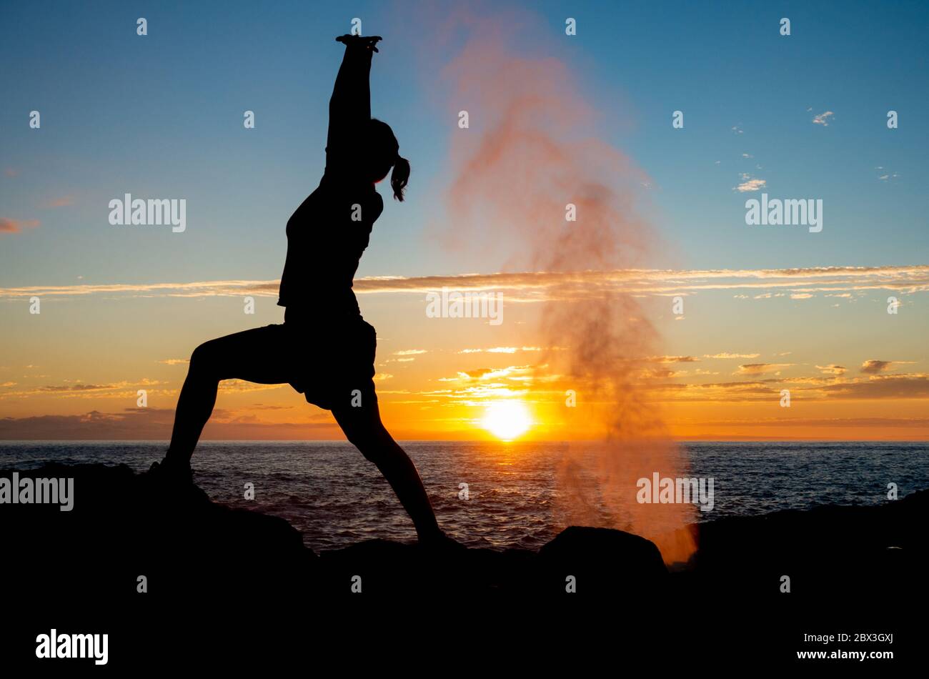 Las Palmas, Gran Canaria, Canary Islands, Spain. 4th June, 2020. A jogger stretches at sunset as water spouts from a lava tunnel on the rugged north coast of Gran Canaria Credit:Alan Dawson/Alamy Live News. Stock Photo