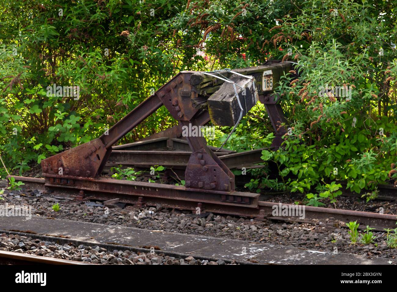 An overgrown buffer stop at the end of a track at the Train Station Grevenbroich, Germany Stock Photo