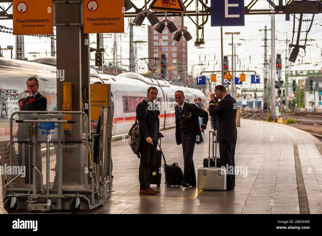 Train conductors at the end of the track in Cologne Central Station take a smoking break. Cologne Train Station, Germany Stock Photo