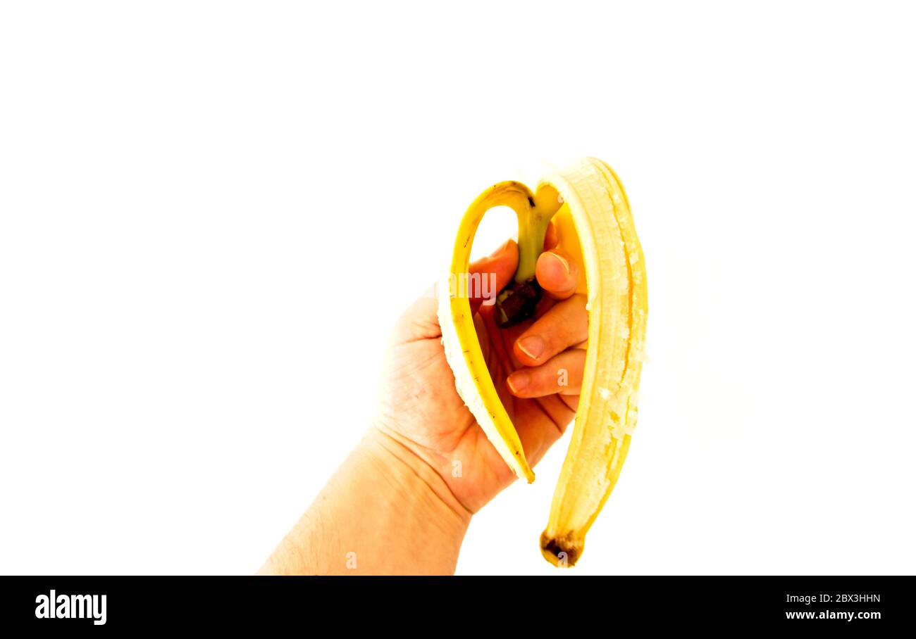 man's hand holding a banana skin on white background Stock Photo