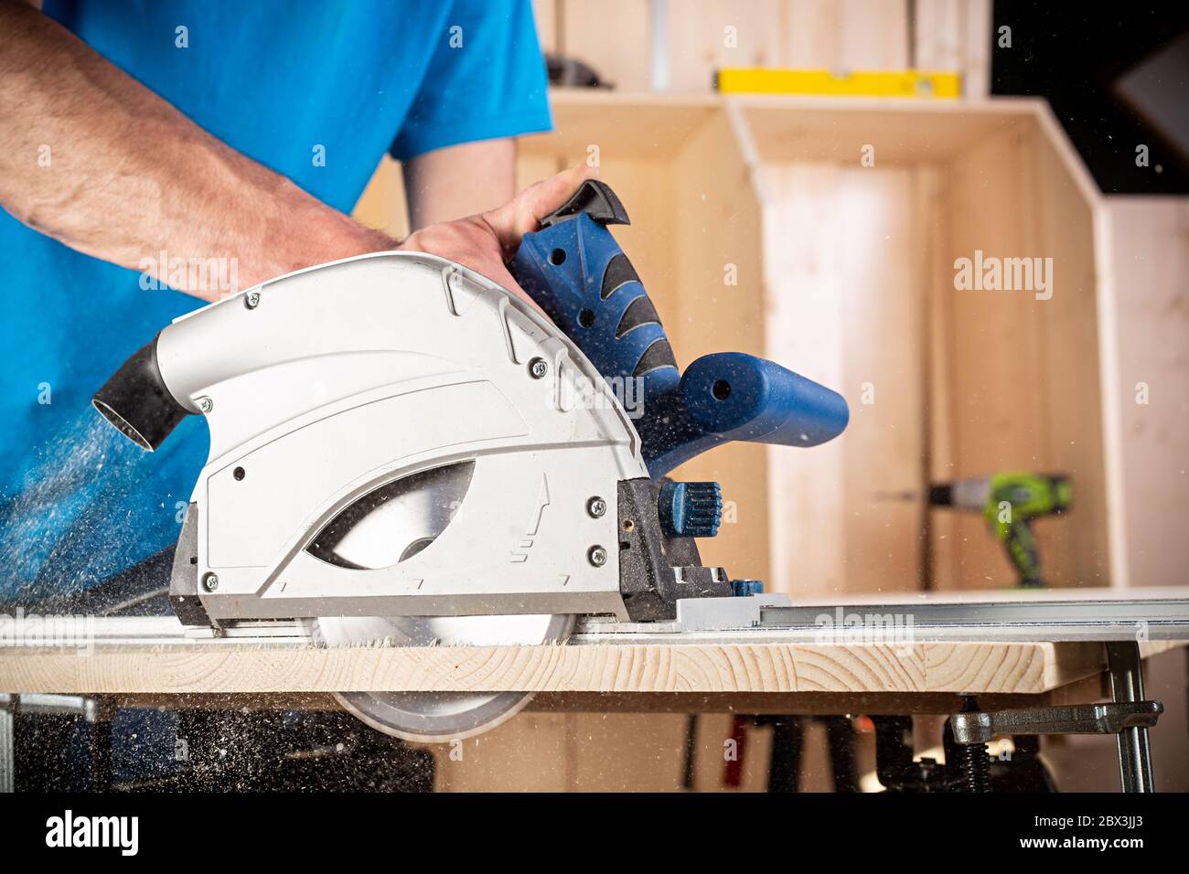 carpenter with hand circular saw at work. closeup of sawing a cut of pine wood woodworking construction tool concept furniture making diy background Stock Photo