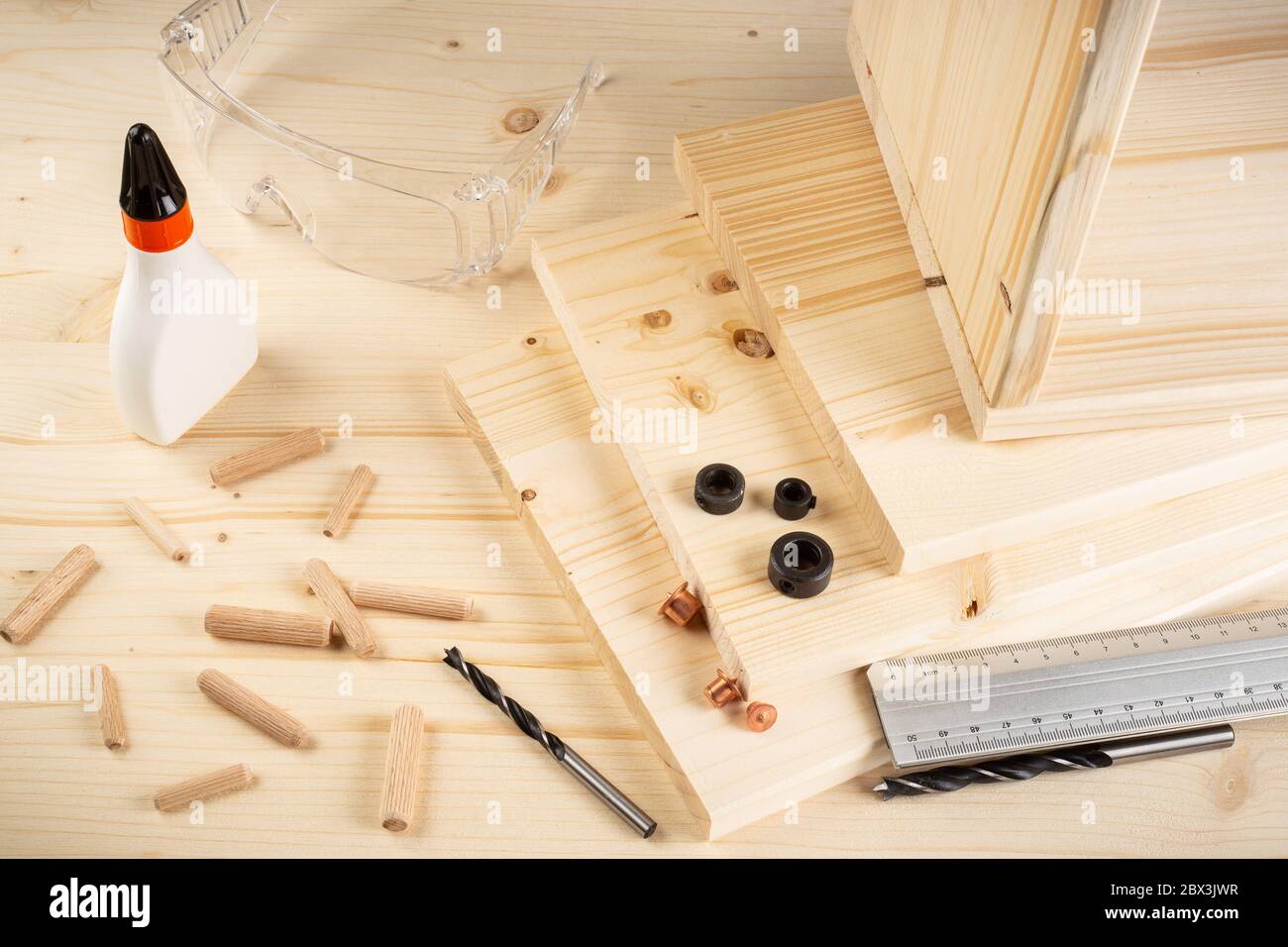 wooden dowel joint pins drill glue wood planks safety glasses and tools on spruce background. Carpenter industry funiture making concept. Stock Photo