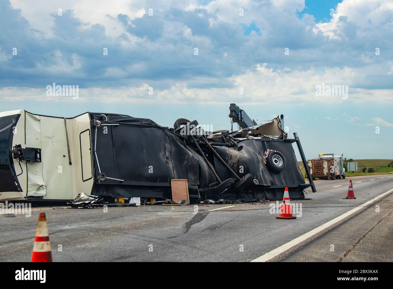 Fifth wheel Recreational Vehicle overturned on a highway with the underside torn up and things spilling out into the roadway after an accident Stock Photo