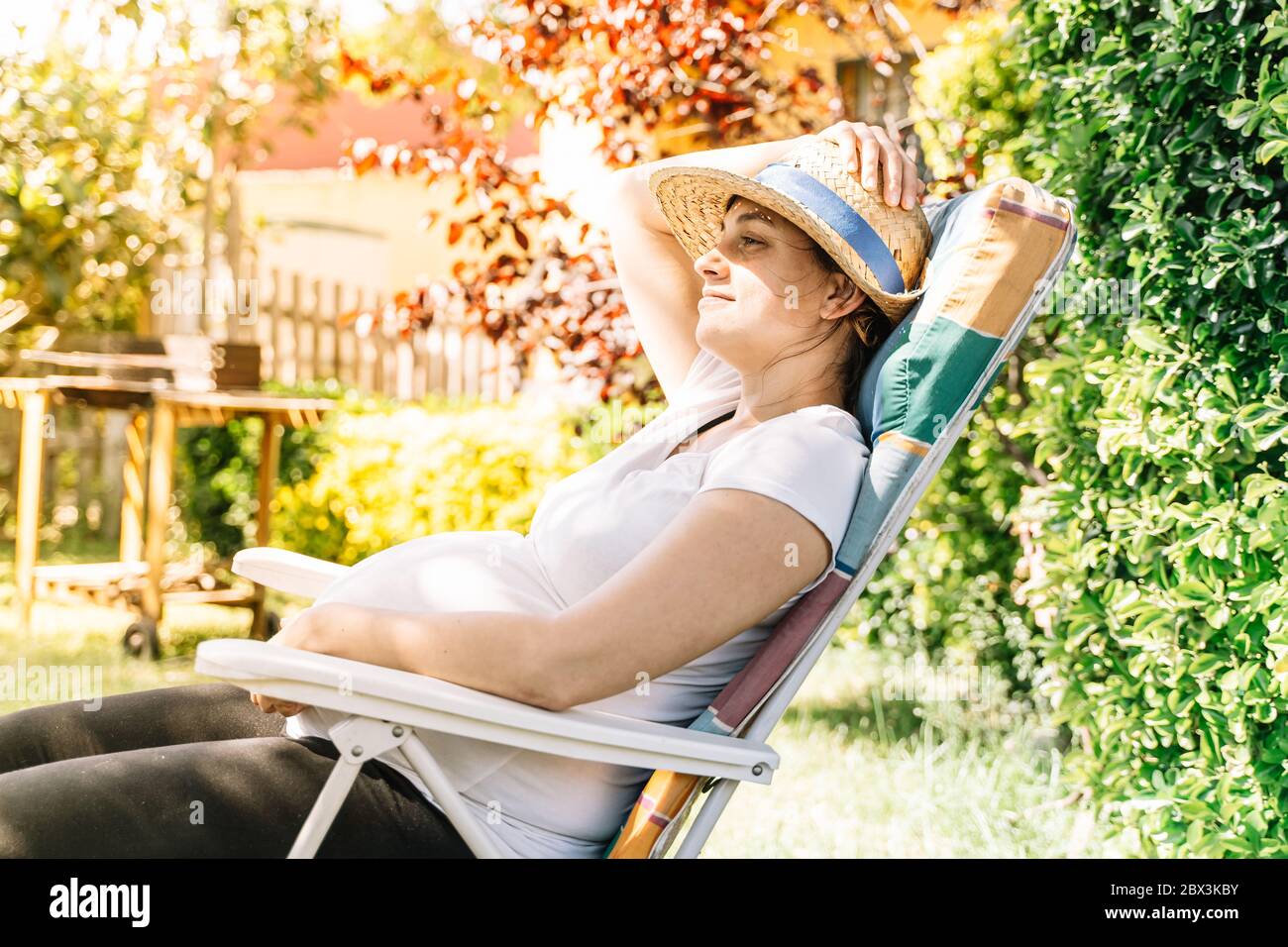pregnant woman sunbathing in the garden in summerpregnant woman sunbathing in the garden in