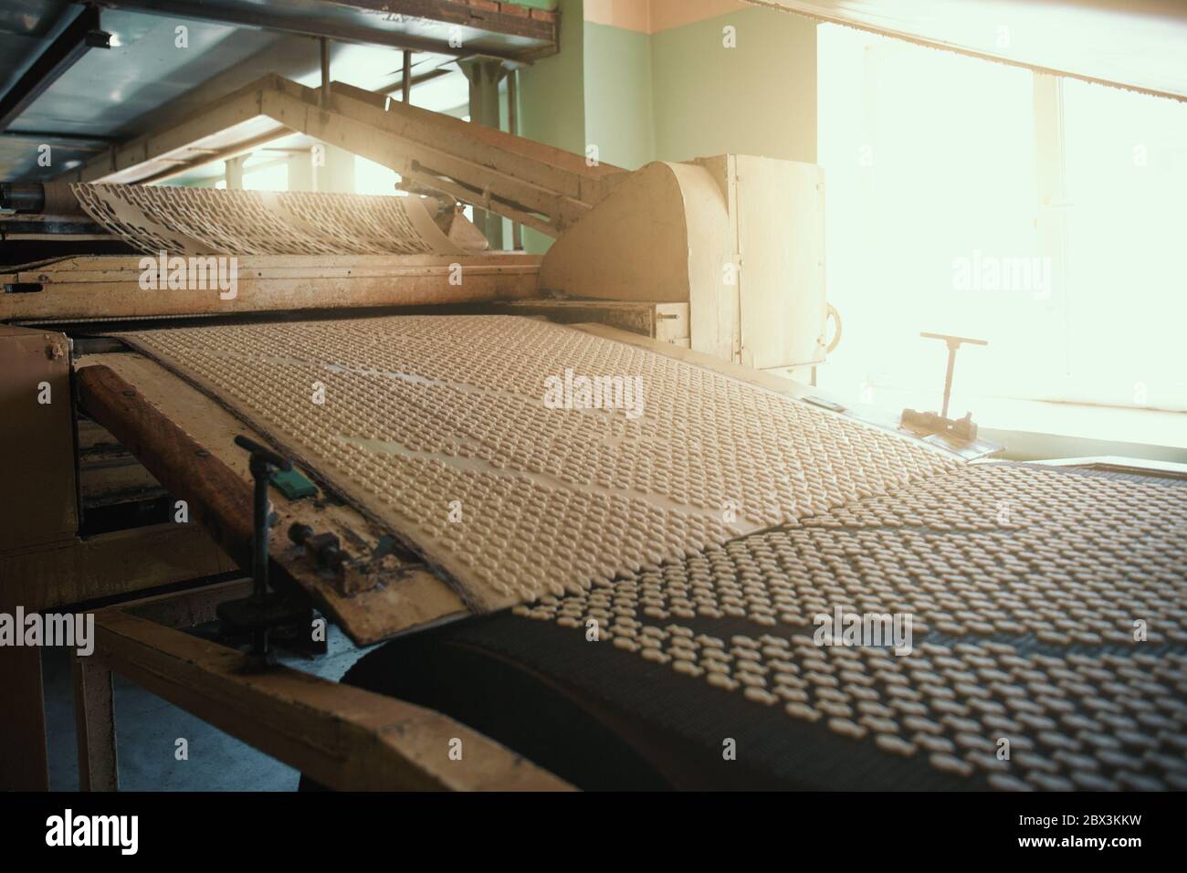 Bakery production line with sweet cookies on conveyor belt, confectionery factory workshop. Stock Photo