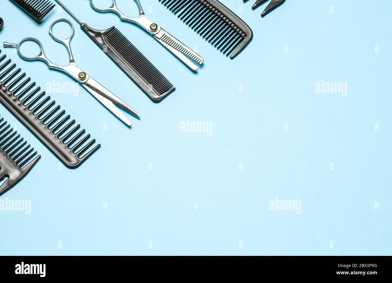 Black combs and combs with scissors on blue background. Copy space for text Stock Photo