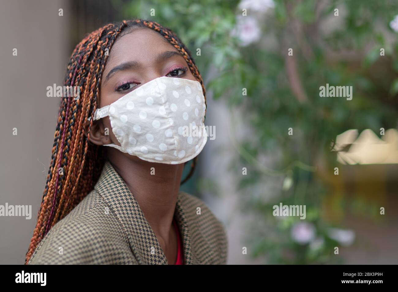 Young dark-skinned girl wearing protective fabric face mask in coronavirus pandemic, COVID-19. Stock Photo