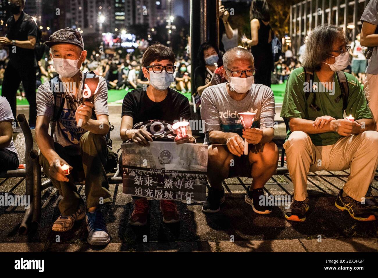 Protesters sits on a barricade with candles during a memorial vigil at