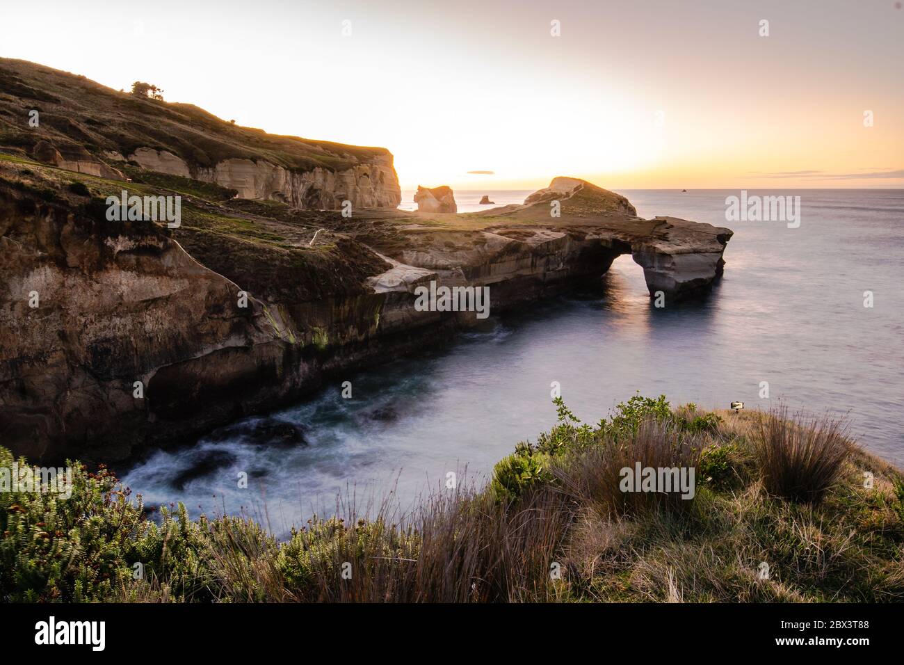 Beautiful sunrise with Natural arch at Tunnel beach, Otago Peninsula, New Zealand Stock Photo