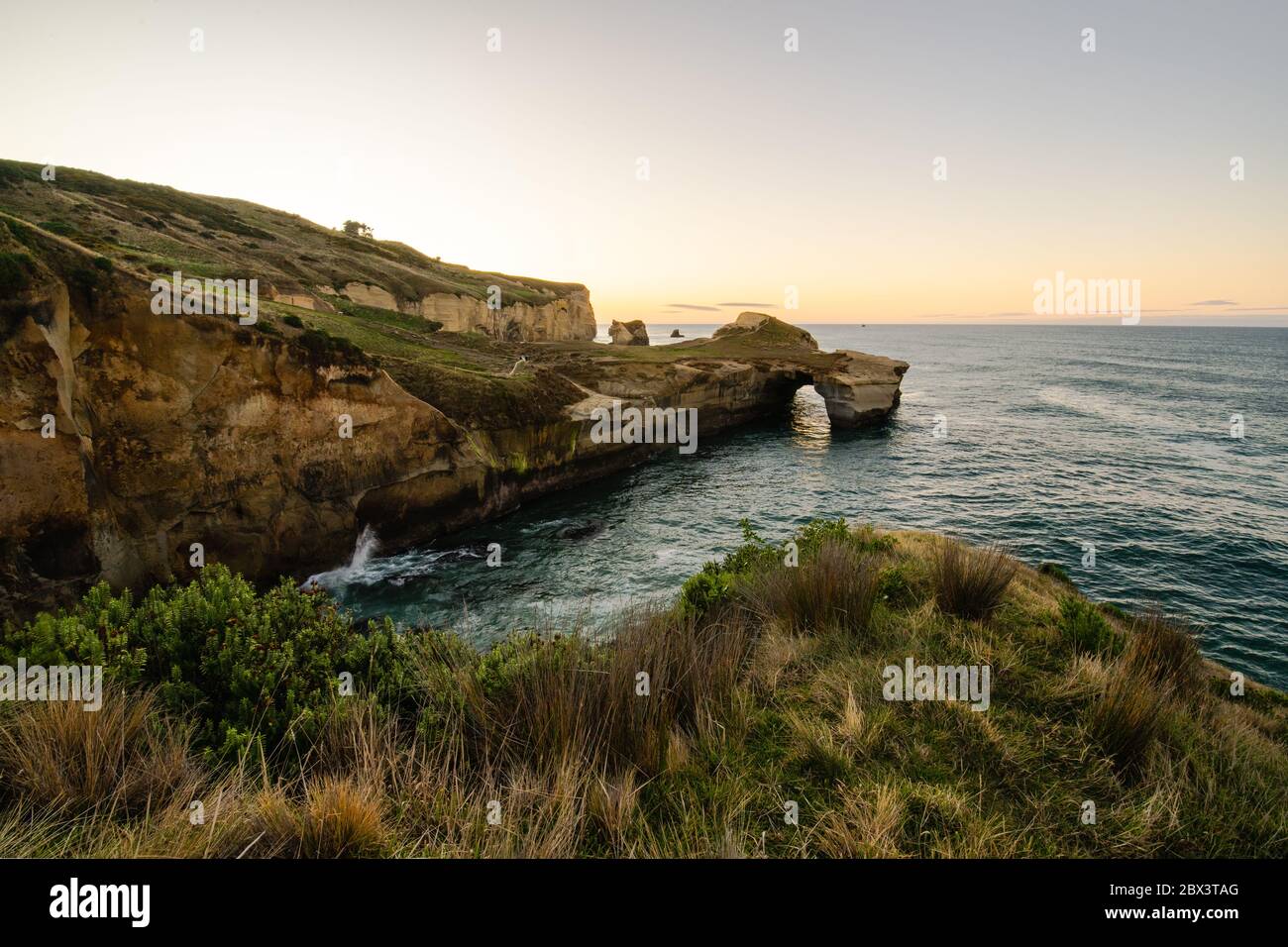 Beautiful sunrise with Natural arch at Tunnel beach, Otago Peninsula, New Zealand Stock Photo