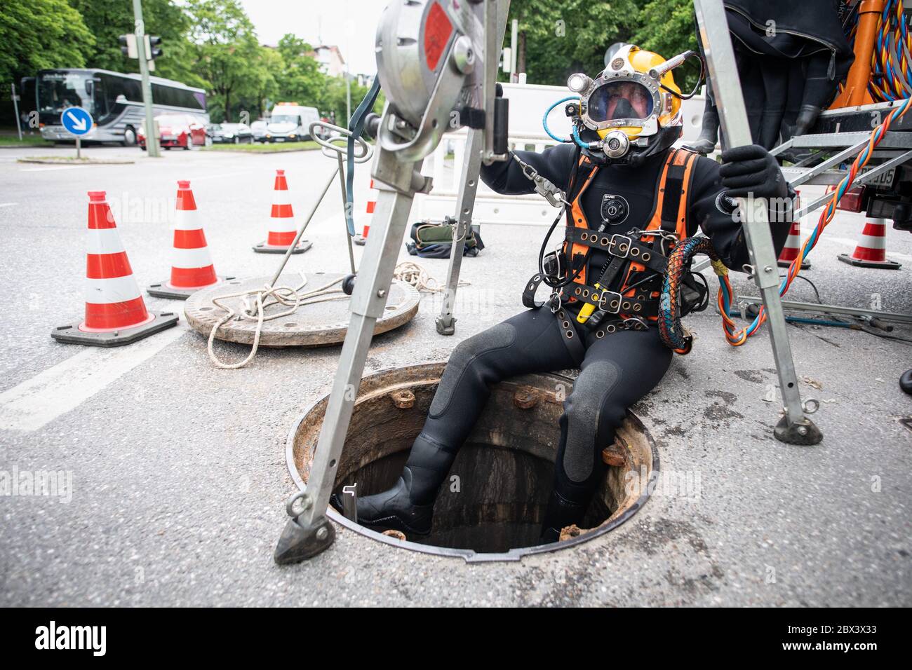 Munich, Germany. 28th May, 2020. Professional diver Marco Weisser climbs out of a shaft at a Munich street crossing after his dive in diving equipment. Weisser inspects culvert installations on behalf of Stadtwerke München, which protect the underground tunnels and stations of the underground railway against groundwater. 400 siphon shafts are maintained by Stadtwerke München to protect the Munich underground railway network. Credit: Matthias Balk/dpa/Alamy Live News Stock Photo