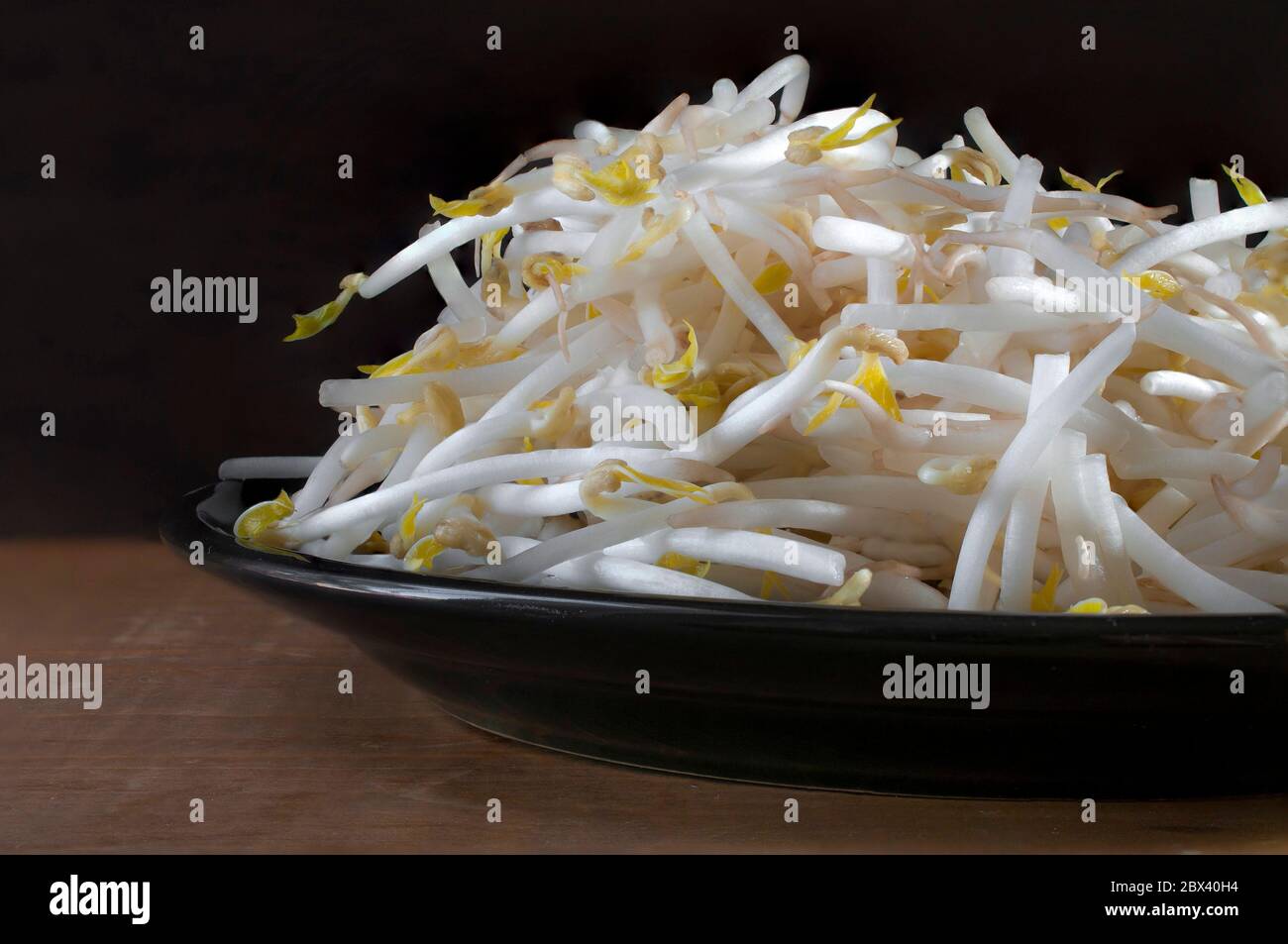 Raw Sprouted mung bean in a black plate and a black background on a wooden table. Ingredient to make Chop suey Stock Photo