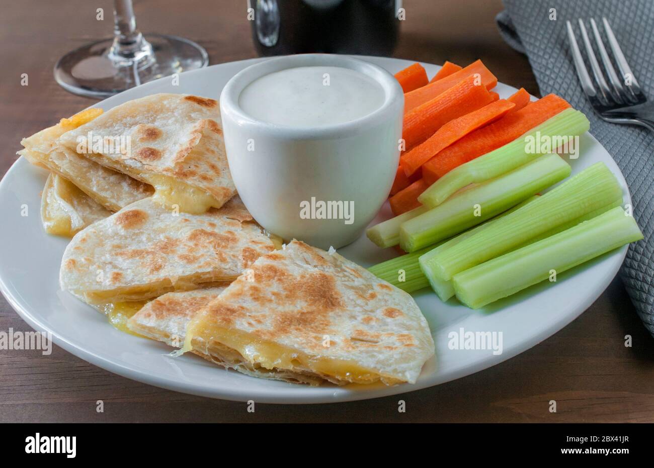 Dipping a quesadilla in ranch dip with celery and carrots sticks on a