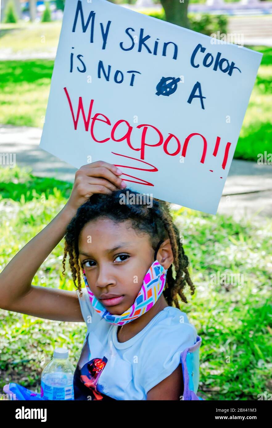 A young AfricanAmerican girl holds a sign while at a protest against