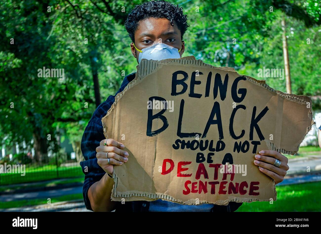 An African-American man holds a sign while at a protest against police brutality, June 4, 2020, at Memorial Park in Mobile, Alabama. Stock Photo