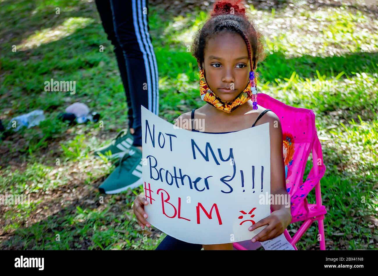 A young African-American girl holds a sign while at a protest against police brutality, June 4, 2020, at Memorial Park in Mobile, Alabama. Stock Photo