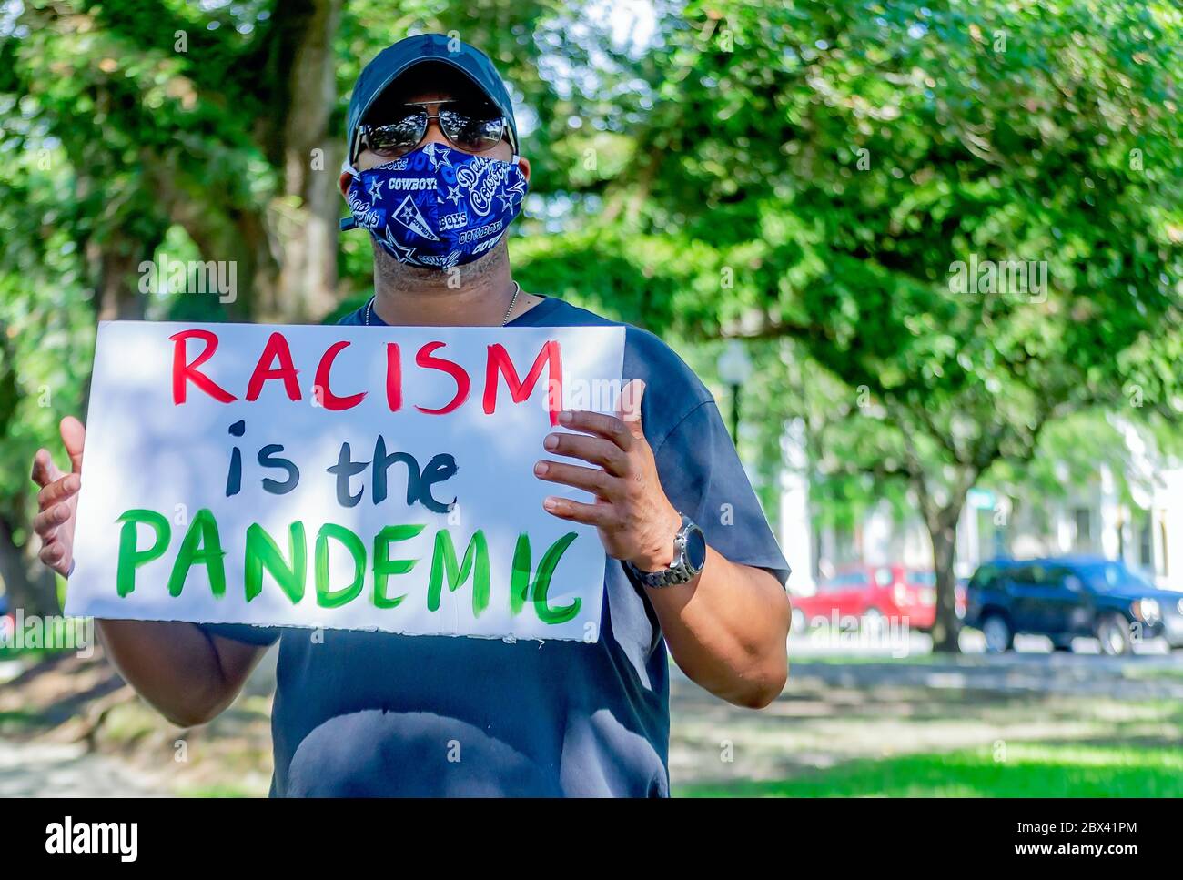 A protestor waves a sign denouncing racism while at a protest against police brutality, June 4, 2020, at Memorial Park in Mobile, Alabama. Stock Photo