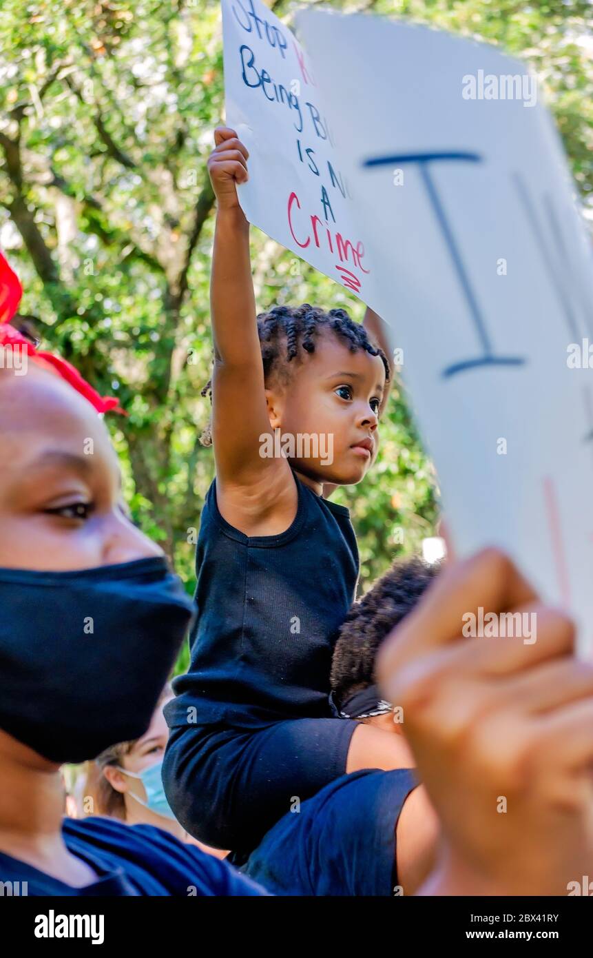A young African-American child holds a sign while at a protest against police brutality, June 4, 2020, at Memorial Park in Mobile, Alabama. Stock Photo