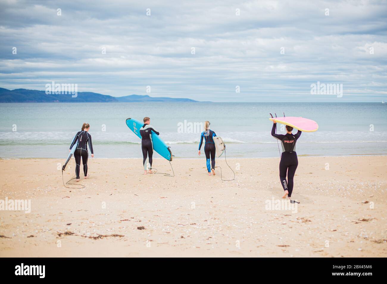 Surf Groms Cloudy Tasmanian Day walking to the water with surf board Stock Photo