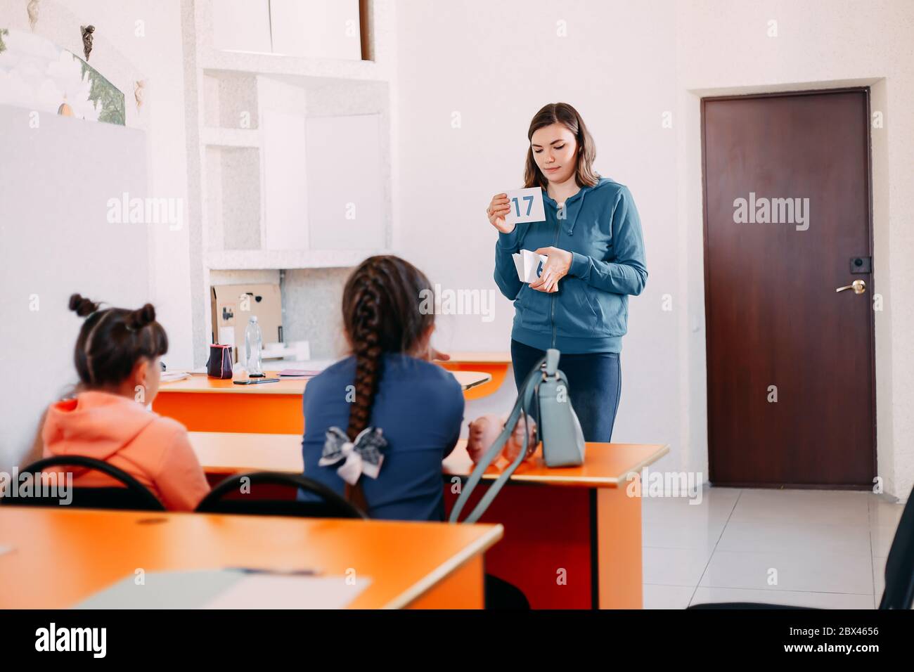 Teacher Teaches Children In Classroom Showind Small Board Stock Photo teacher-teaches-children-in-classroom-showind-small-board-stock-photo