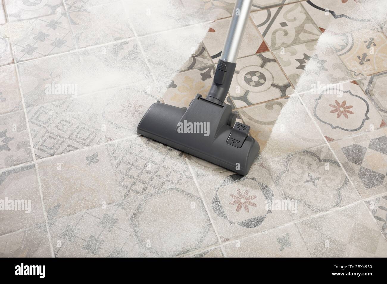 cleaning floor with modern vacuum cleaner in kitchen room. Concept of easy cleaning with cyclone vacuum cleaner Stock Photo